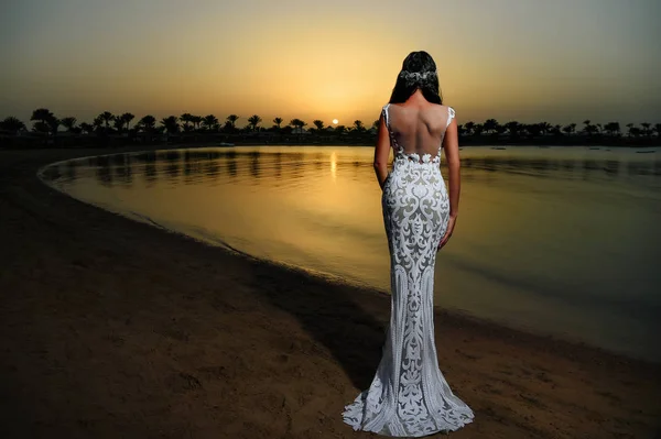 Vrouw in witte jurk in sunset beach — Stockfoto