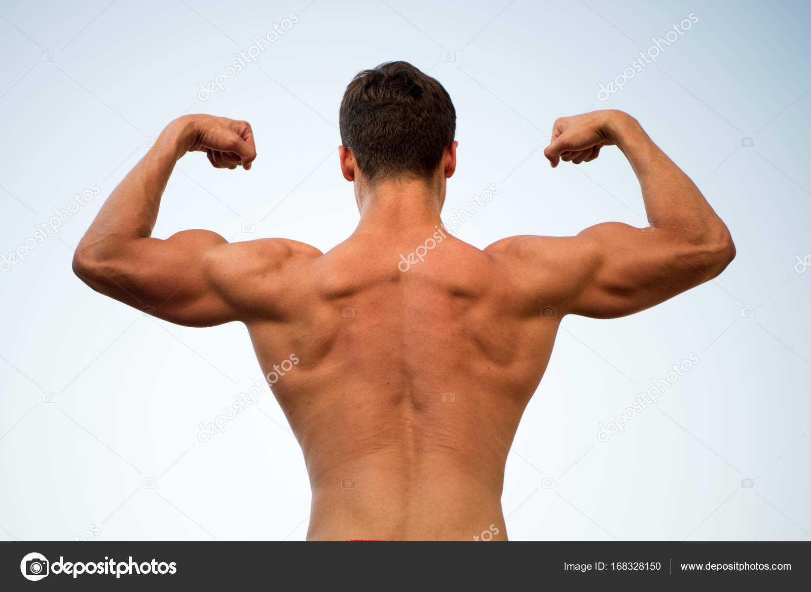 Man or sportsman flexing arms with fists, back view Stock Photo by