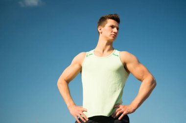 Adam vücut geliştirmeci mavi gökyüzü üzerinde poz