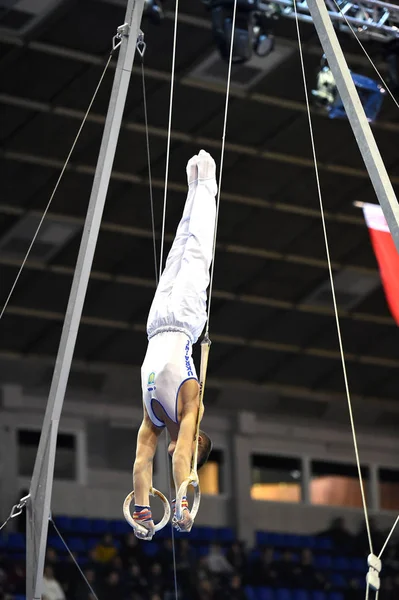 Mannelijke Turner uitvoeren op stationaire gymnastiek ringen — Stockfoto