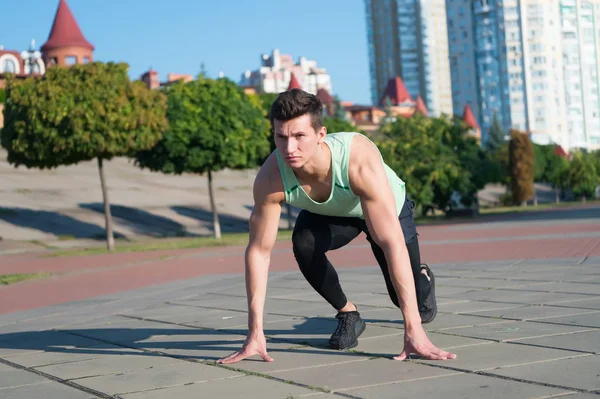 Ajuste macho en chándal y zapatillas de correr en el paisaje urbano — Foto de Stock