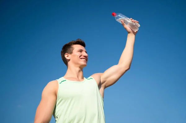 Atleet glimlachend in groene tshirt op blauwe hemel — Stockfoto