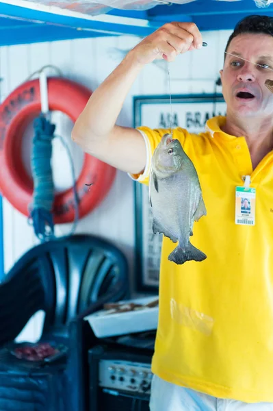 Homem excitado em camiseta amarela segurando peixes on-line — Fotografia de Stock