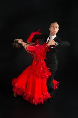 Dans eden balo çifti siyah arka planda yalnız poz verir.