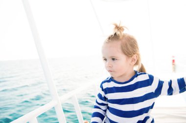 Mavi deniz suyu üzerinde yelken çizgili gömlekli çocuk denizci
