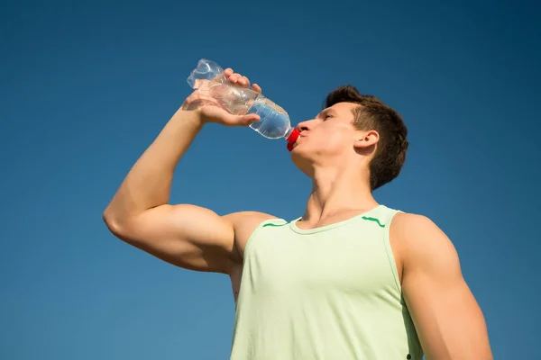 Mies juo vettä pullosta aurinkoisena päivänä — kuvapankkivalokuva