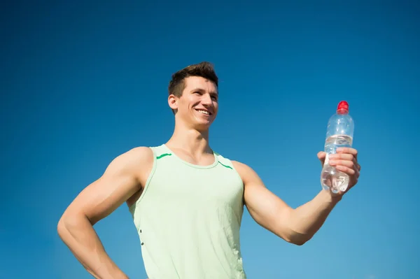 นักกีฬาที่ยิ้มในเสื้อสีเขียวบนท้องฟ้าสีฟ้า — ภาพถ่ายสต็อก