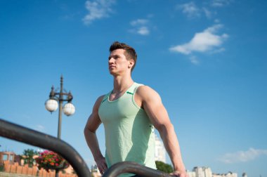 Adam vücut geliştirmeci mavi gökyüzü üzerinde poz