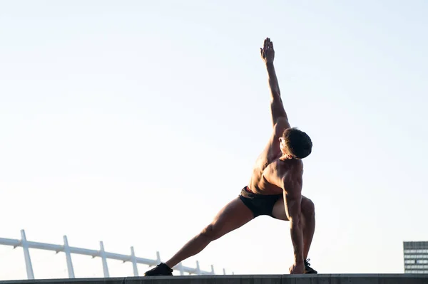 Man stretching hands and legs on roof — Stock Photo, Image