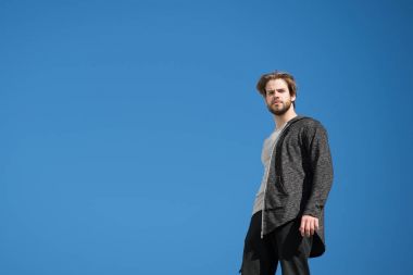 Gri ceketli adam mavi gökyüzünde duruyor.