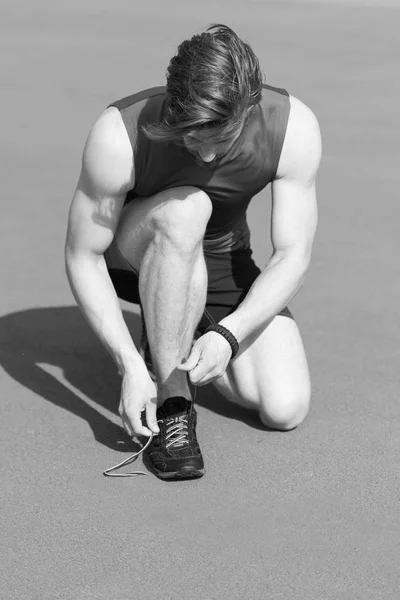 Runner, atletisk skægget mand med muskelbånd sko snørebånd - Stock-foto