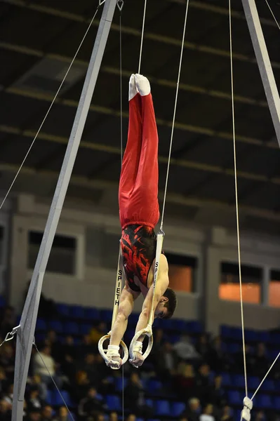 Mannelijke Turner uitvoeren op stationaire gymnastiek ringen — Stockfoto