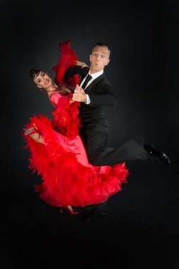 Dans eden balo çifti siyah arka planda yalnız poz verir.