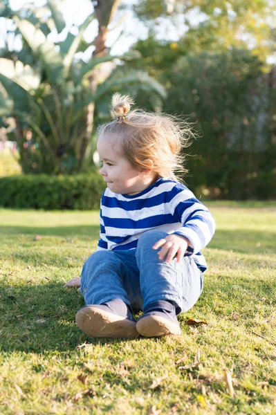 Ragazzo con i capelli biondi in abiti blu sedersi sull'erba — Foto Stock