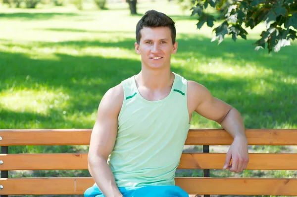 Atleta sonriendo en banco de madera en el parque — Foto de Stock