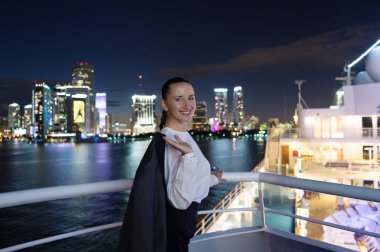 Miami, ABD 'de ceketli bir kadın balkonda gülümsüyor.