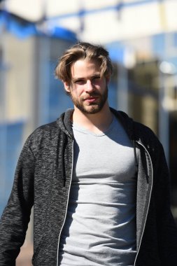 Gri tişörtlü adam güneşli bir günde yürüyor.