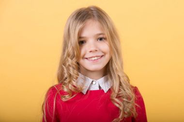 Turuncu arka planda kıvırcık sarı saçlı çocuk.