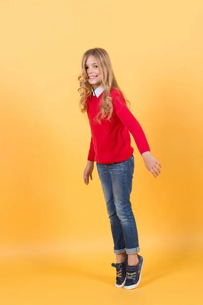 Mädchen in rotem Pullover und Jeans stehen auf Zehenspitzen — Stockfoto