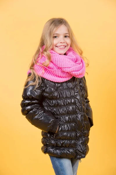 Mädchen in schwarzem Mantel und rosa Schal auf orangefarbenem Hintergrund — Stockfoto