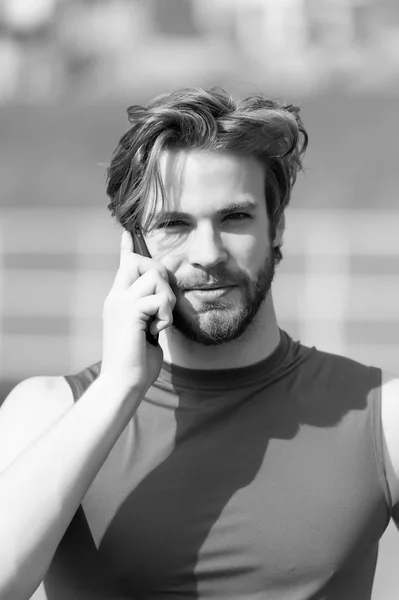 Спортивный бородатый счастливый мужчина с мускулистым телом держит мобильный телефон — стоковое фото