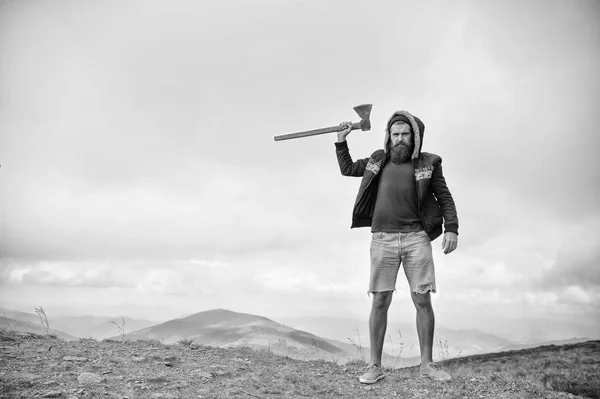 Lumberjack homem barbudo brutal com pé machado no topo da montanha — Fotografia de Stock