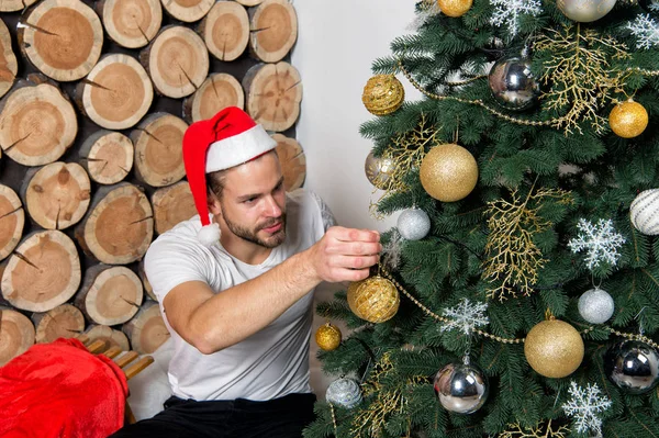 Man in santa claus hat decorate Christmas tree — Stock Photo, Image