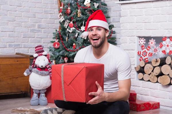 Man in Kerstman hoed zitten op de vloer bij open haard — Stockfoto
