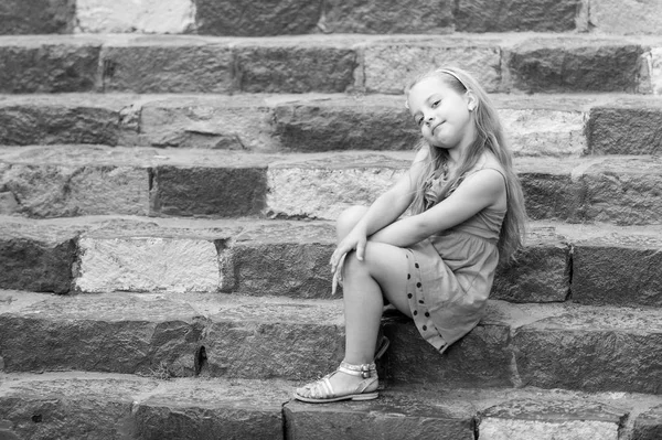 Маленька усміхнена дівчинка в блакитній сукні на барвистих сходах — стокове фото