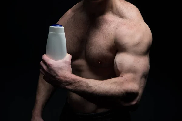 Bottiglia di shampoo in mano dell'uomo con corpo muscolare — Foto Stock