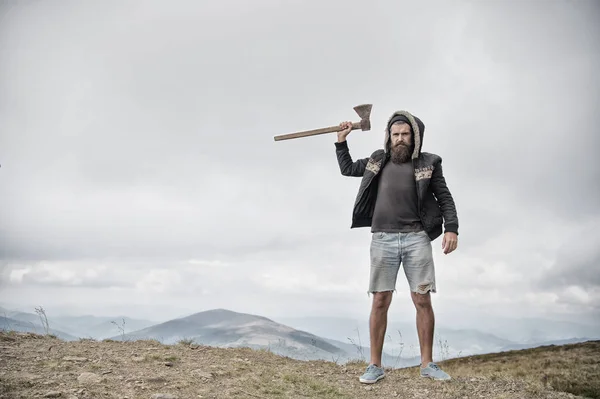 Hipster brutale uomo barbuto con ascia stand sulla cima della montagna — Foto Stock