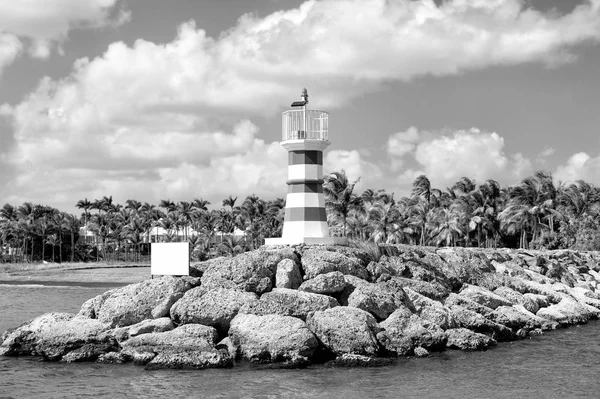 Faro sobre piedras cerca del agua y palmeras — Foto de Stock