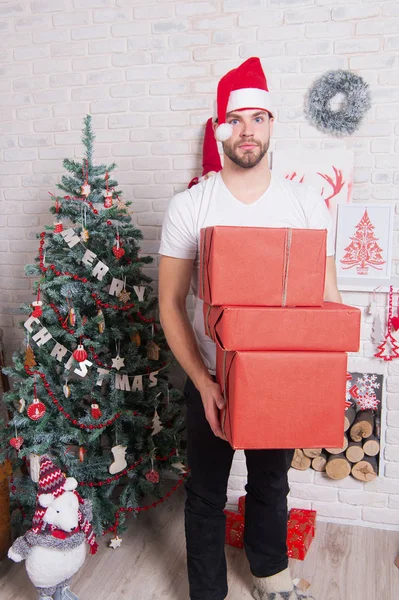 Macho i röd hatt håll inslagna presenter — Stockfoto