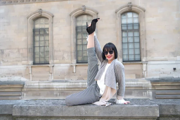 Chica feliz hacer la pierna dividida estiramiento ejercicio en valla de piedra — Foto de Stock