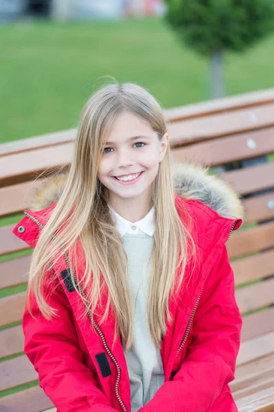 Chica de abrigo rojo sentarse en el banco en el parque — Foto de Stock