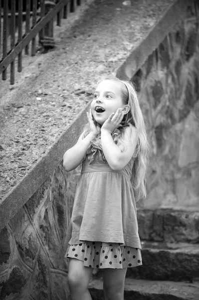 Маленькая девочка с удивленным лицом в синем платье на открытом воздухе — стоковое фото