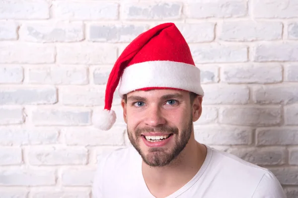 白いレンガの壁に赤いサンタ帽子の男の笑顔 — ストック写真