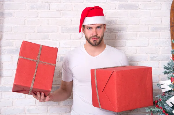 Macho i christmas hat hålla inslagna presenter — Stockfoto