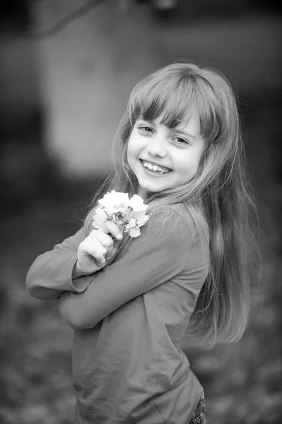 Kleine babymeisje met lachende gezicht houden van roze sakura bloesem — Stockfoto