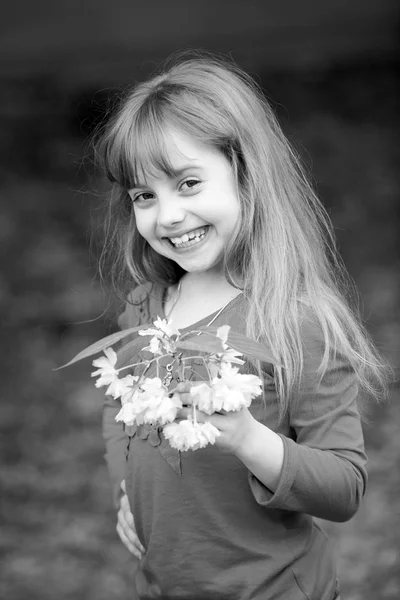 Niña pequeña con la cara sonriente sosteniendo flor de sakura rosa —  Fotos de Stock