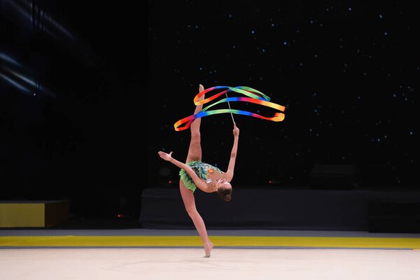 гимнастка выступает на соревнованиях по художественной гимнастике
