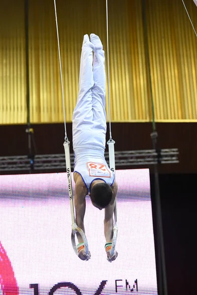 Gimnasta masculina que actúa en anillos gimnásticos estacionarios — Foto de Stock