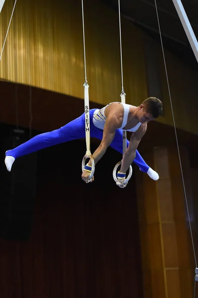 Αρσενικό gymnast εκτελεί την εν στάσει Γυμναστικά δαχτυλίδια — Φωτογραφία Αρχείου