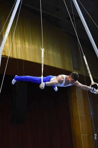 Мужская гимнастка выступает на стационарных гимнастических кольцах — стоковое фото