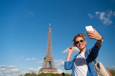 Paris, Fransa 'daki Eyfel Kulesi' nde mutlu bir kadın selfie çekiyor.
