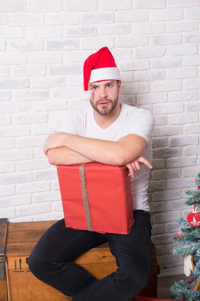 Man santa met verpakt kerstcadeau zitten op houten doos — Stockfoto