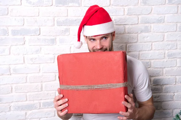 Mann mit listischem Gesicht im Weihnachtsmannhut hält rote Schachtel in der Hand — Stockfoto