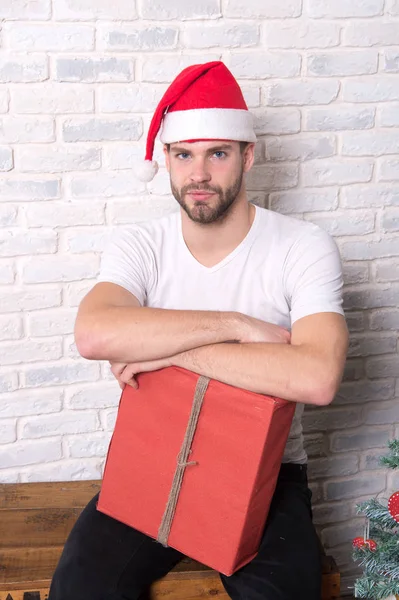 Macho in christmas hat hold wrapped present — Stock Photo, Image