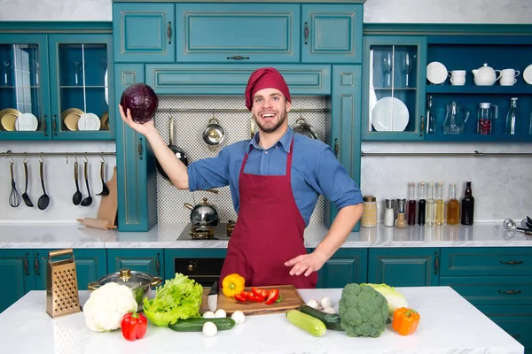 Hombre en sombrero de chef sonrisa con col púrpura en la cocina —  Fotos de Stock