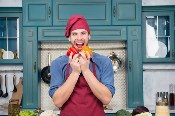 Хлопець у капелюсі шеф-кухаря посміхається з червоним та апельсиновим перцем — стокове фото